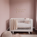 Custom baby name sign reading eleanor grace on a dusty pink nursery wall above a white crib