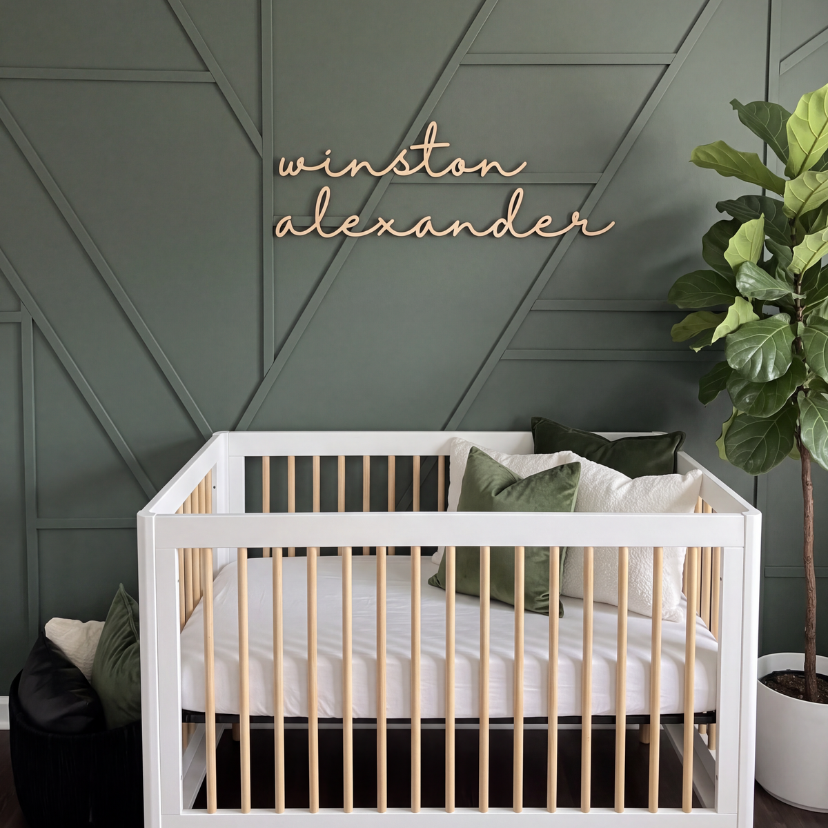 Nursery name sign reading winston alexander on a green panelled wall above a white crib