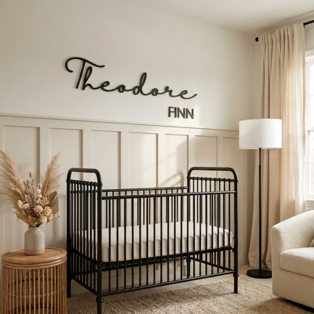 Black cursive name sign above a black crib in a neutral nursery