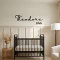 Wood nursery name sign reading Theodore Finn in black on a cream panelled wall