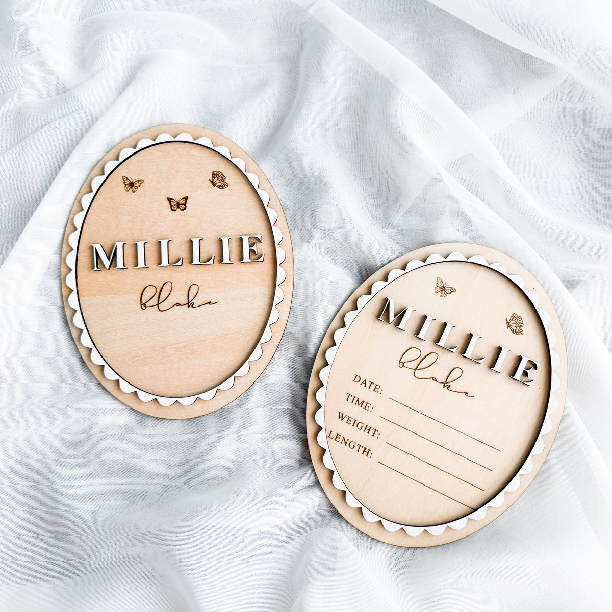 Butterfly baby name sign and matching birth stats sign side by side on white fabric