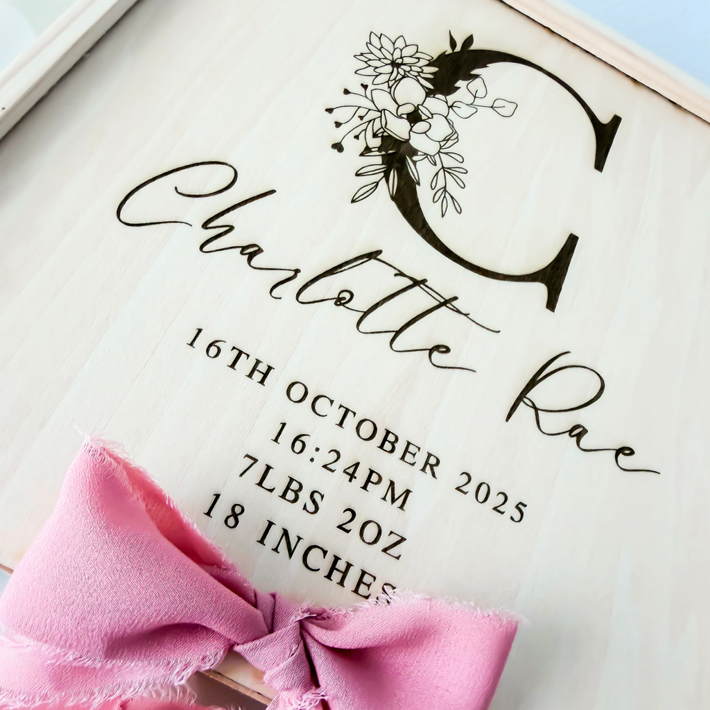 Close-up of the engraved floral initial and birth stats on the keepsake box lid