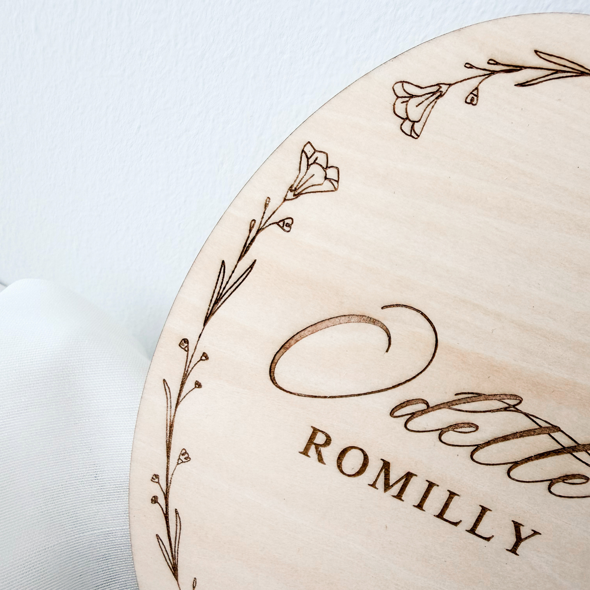 Close-up of the engraved wildflower wreath and script name on the birch basswood name sign
