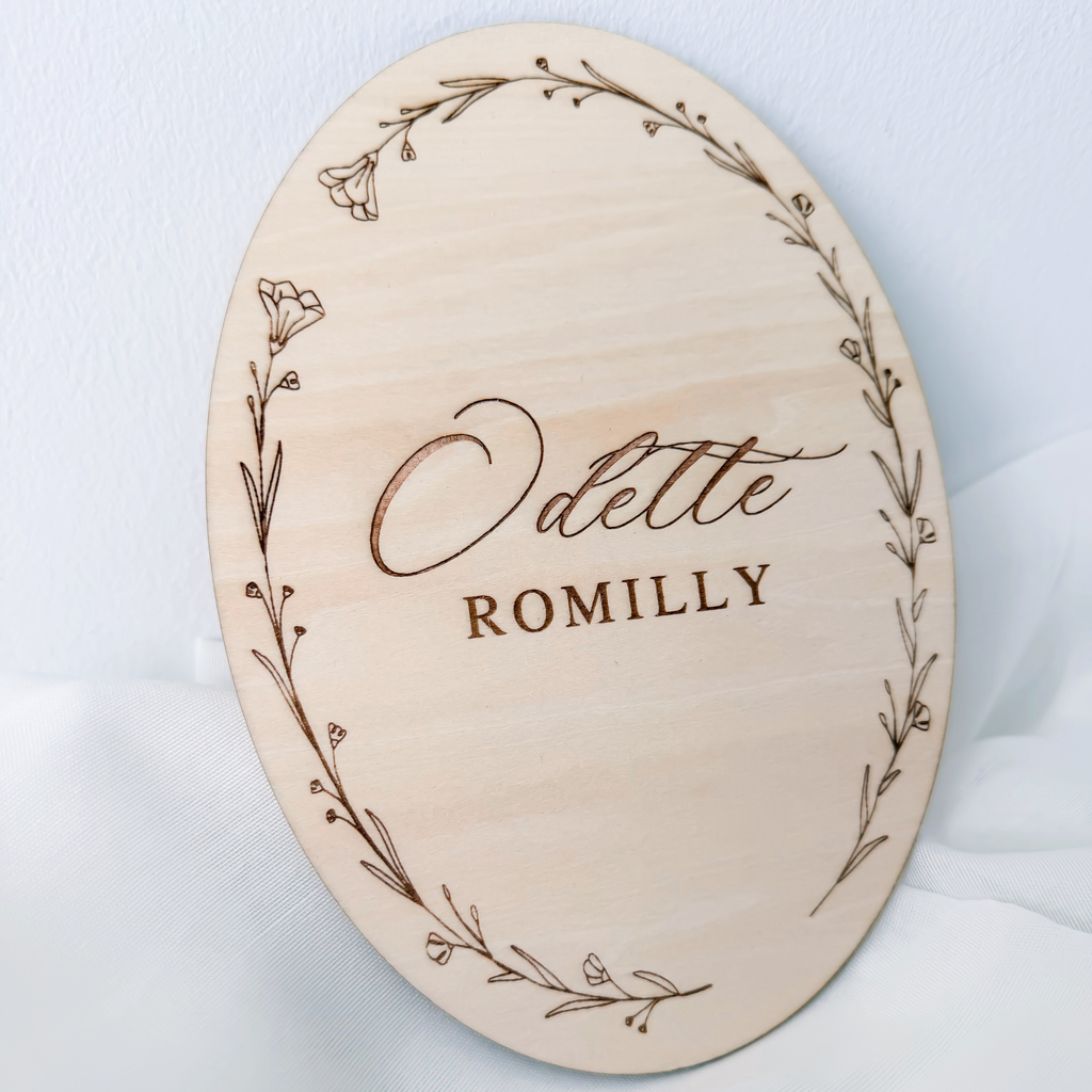Angled view of the oval name sign showing the full engraved wildflower wreath border